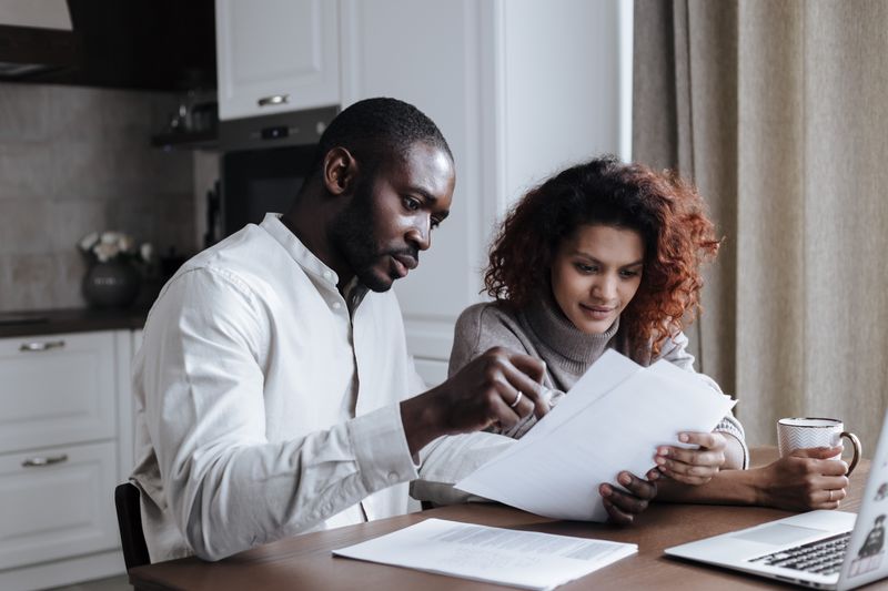 Couple working together on documents at home interior using a laptop.