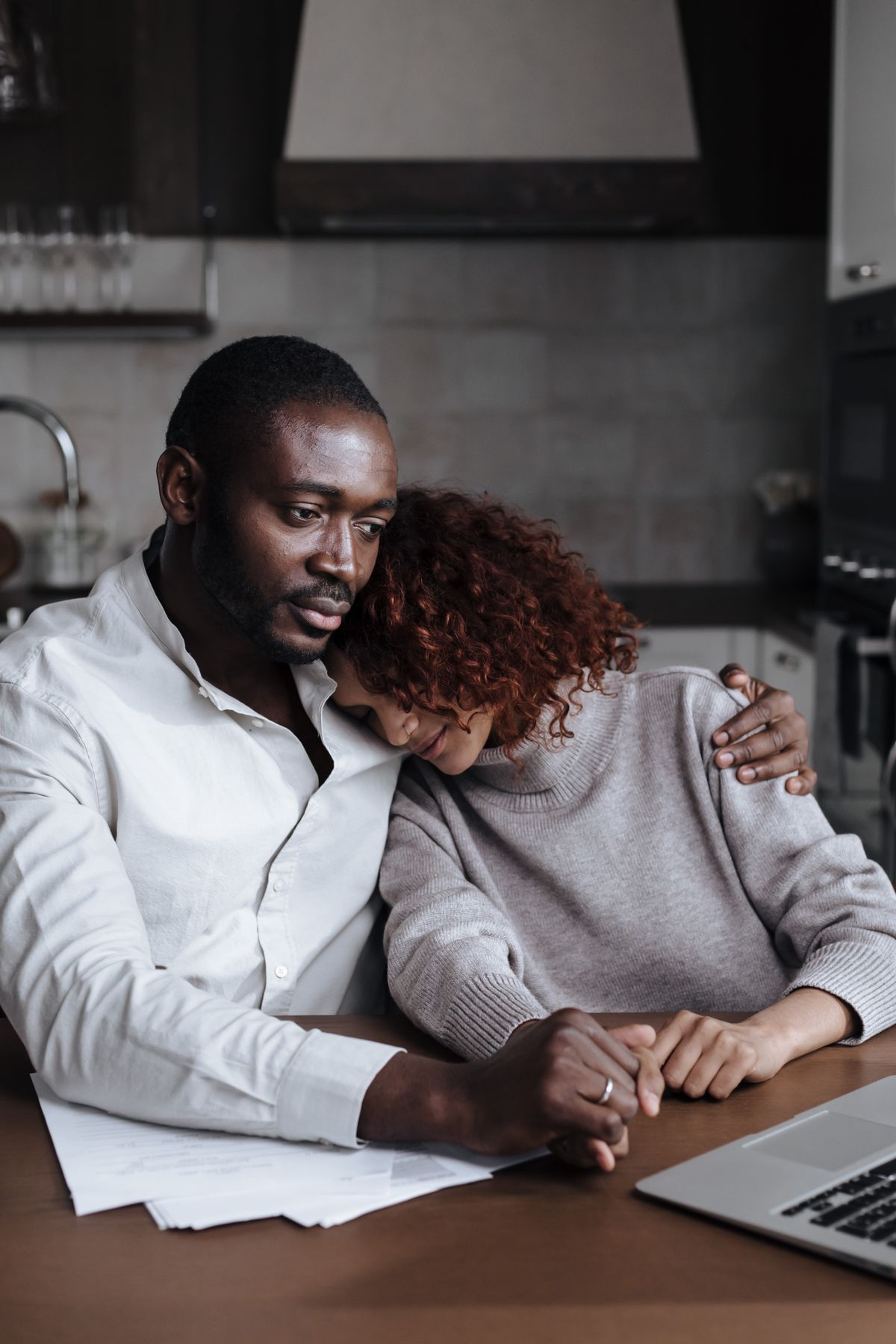 A man comforting a grieving woman at the kitchen table