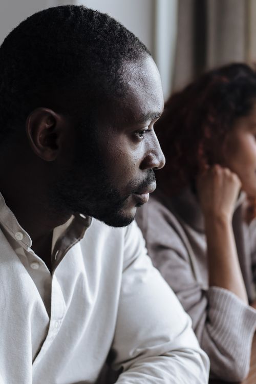 Free A thoughtful couple sits indoors, capturing a moment of introspection and connection. Stock Photo