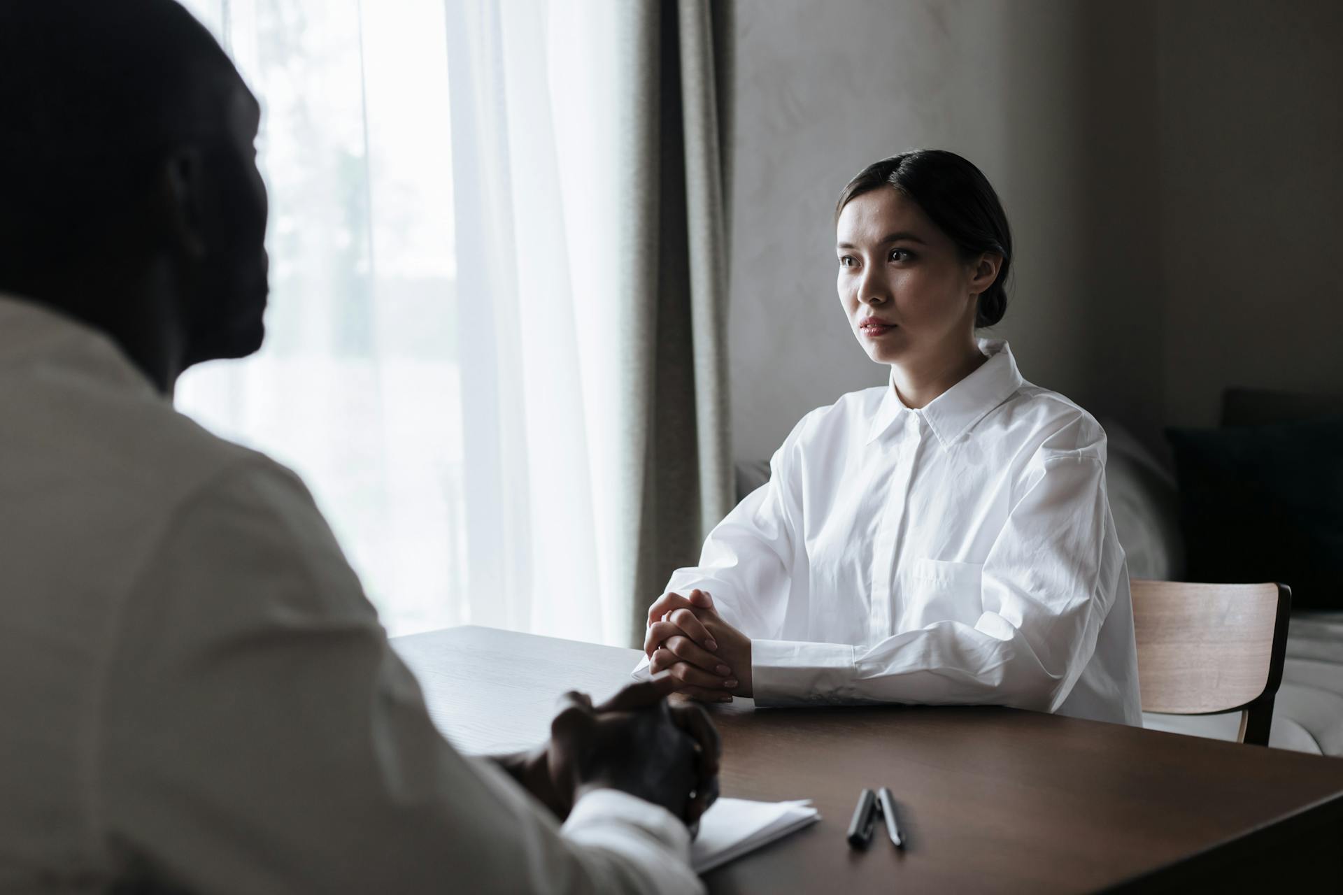 Two professionals engaged in a thoughtful interview in a well-lit room.