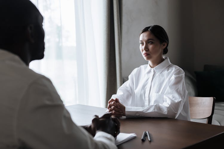 Man And Woman Sitting On Opposite Sides Of Desk