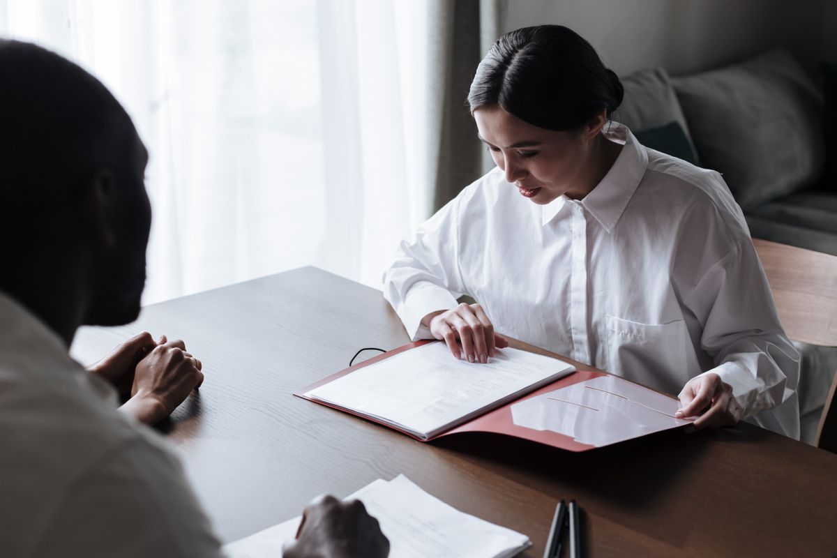 Professional businesswoman discussing documents with colleague at a desk