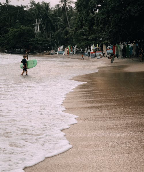 Surfer Walking Out of Water onto Beach