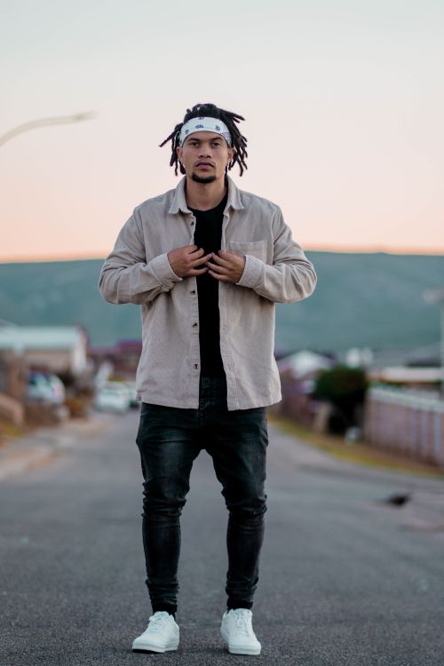 Free Portrait of a young man standing on a street in Kariega, South Africa, showcasing modern casual style. Stock Photo