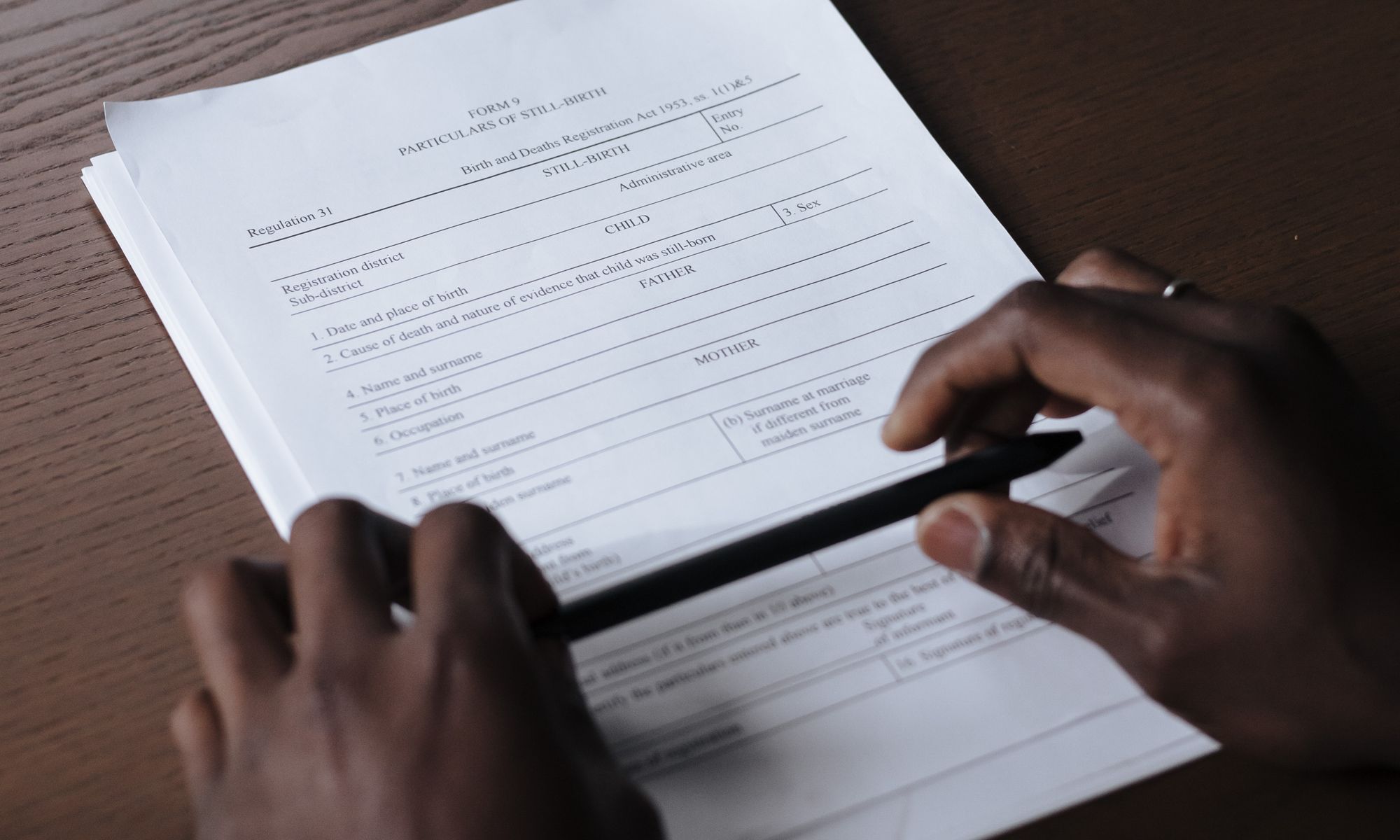 Hands holding a pen while reviewing documents on a table