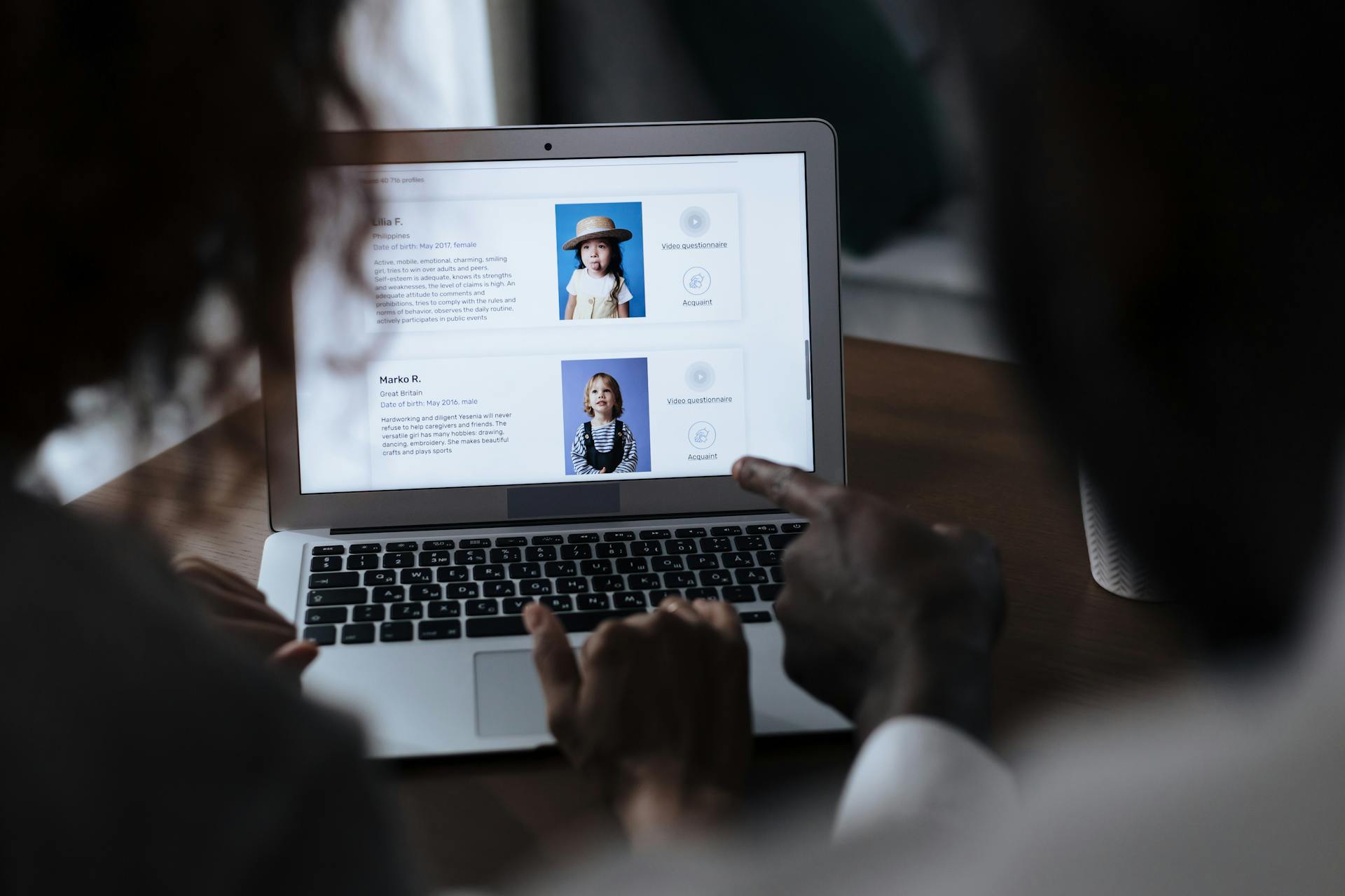 Man and Woman in Front of a Laptop and Choosing Children Profiles