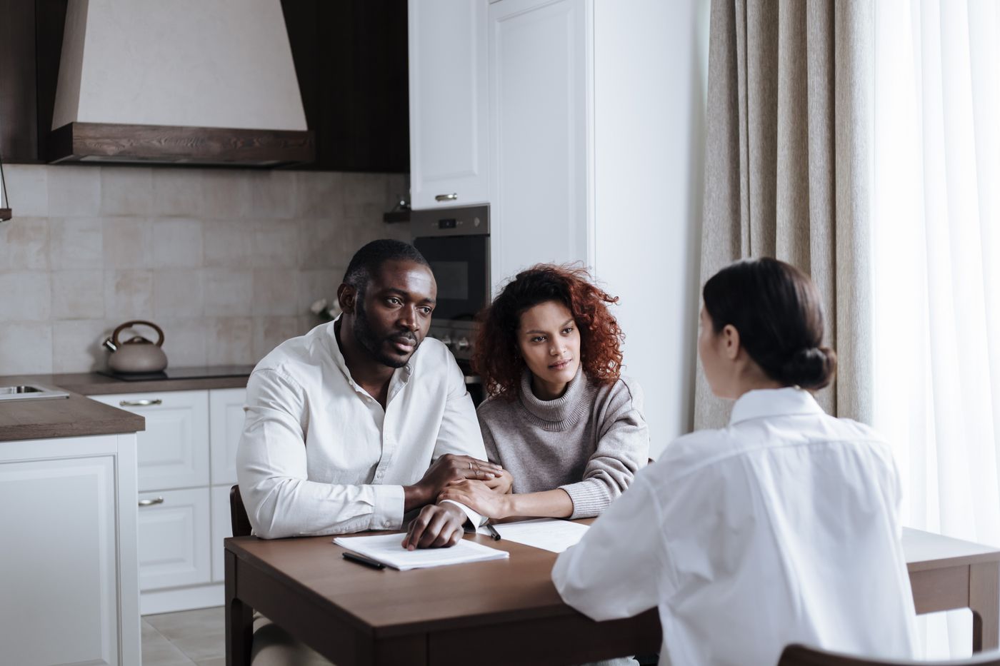 Three adults talking together around a table at home