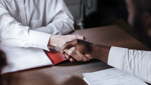Close-up of a diverse business handshake over documents, symbolizing agreement and collaboration.