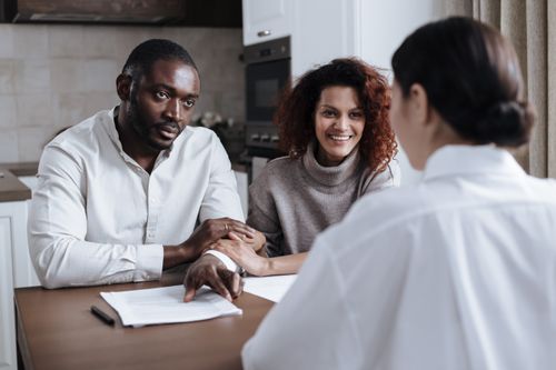 Free Happy couple consulting with a professional advisor in a home setting. Stock Photo