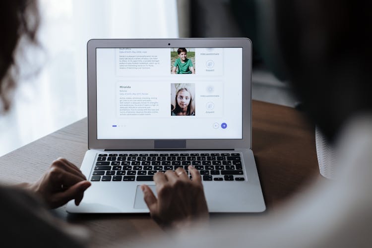 Unrecognizable Couple Looking At Laptop Screen Displaying Adoption Page 