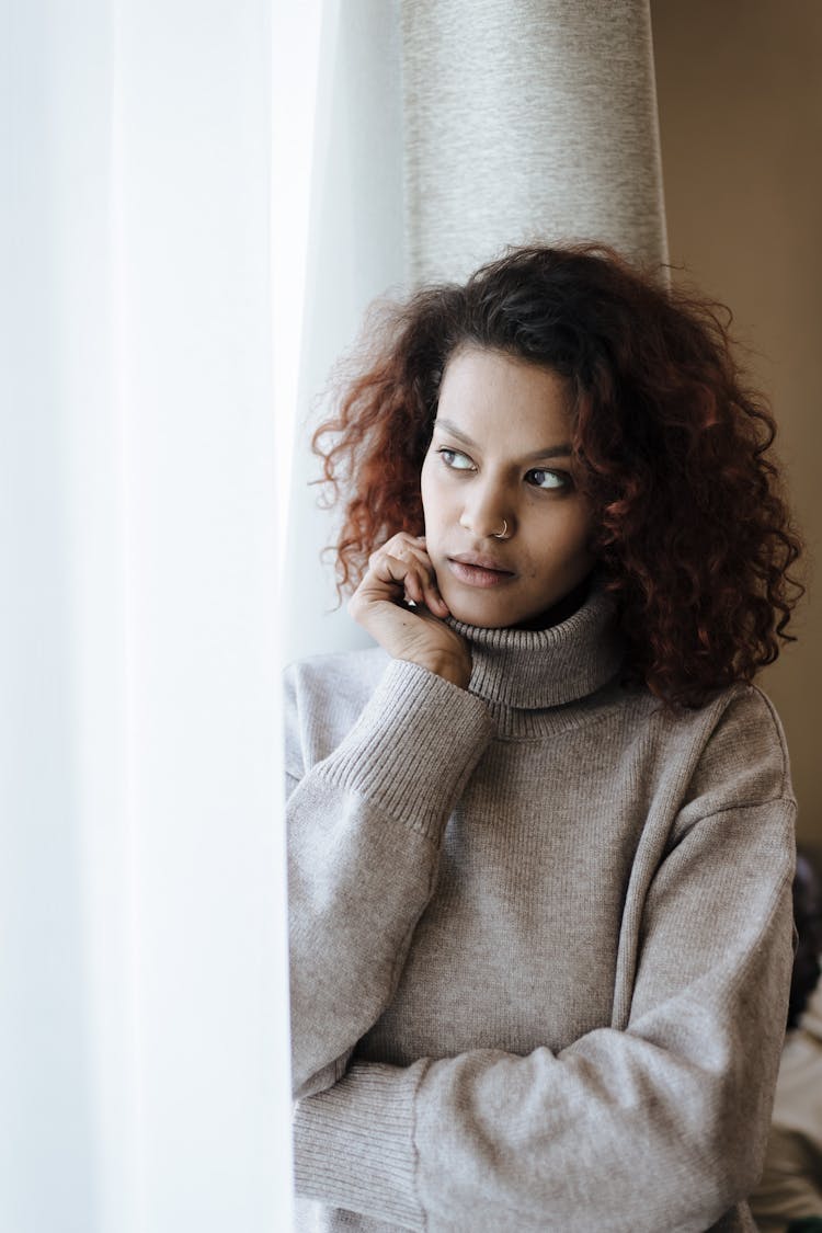 Woman Looking Through Window At Home