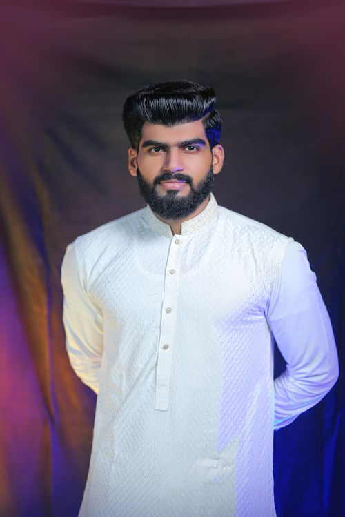 Free Studio portrait of a man wearing a traditional white kurta, set against a colorful gradient backdrop. Stock Photo