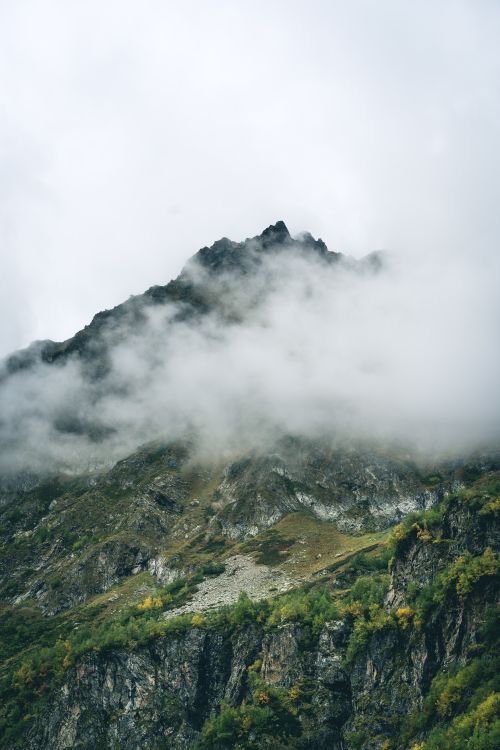 Free Serene mountain peak enveloped in dense fog, showcasing nature's tranquility. Stock Photo