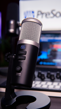 Vertical shot of a professional microphone and control panel in a recording studio setting.