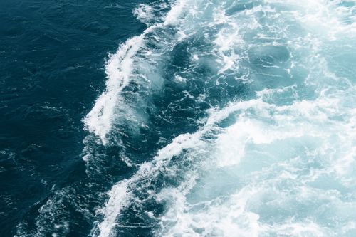 Free Powerful ocean waves crash creating seafoam, captured from above showcasing the vibrant blue seascape. Stock Photo