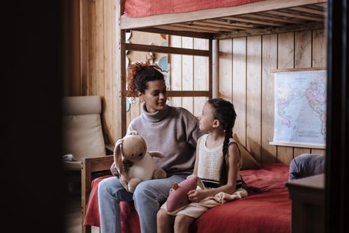 Free Mother and daughter sitting together, sharing a tender moment indoors. Warm and inviting home setting. Stock Photo