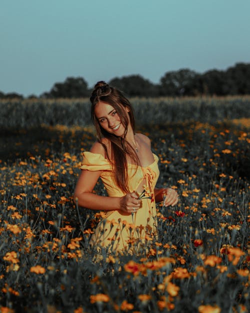 Beautiful Woman in Yellow Dress Standing on a Flower Field