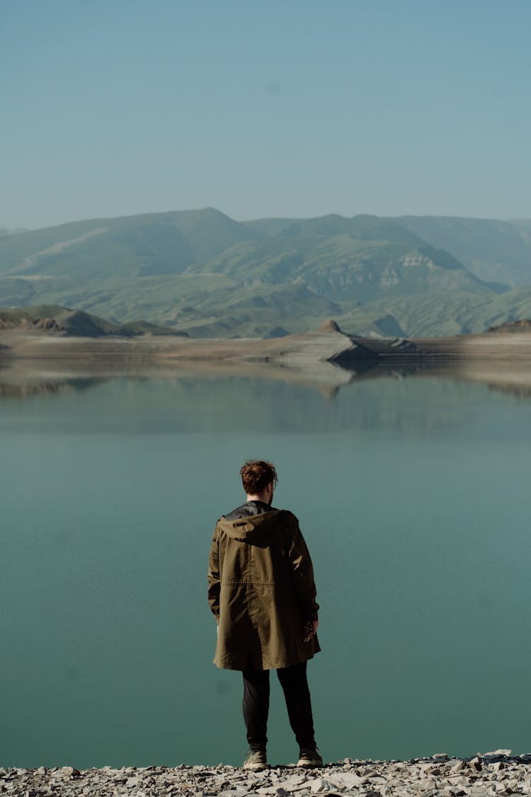 Backview Of Man Standing On Lakeside 