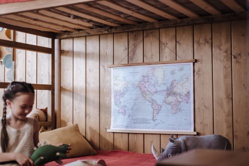 Free A cheerful child in a wooden bedroom with a map, playing with toys. Stock Photo