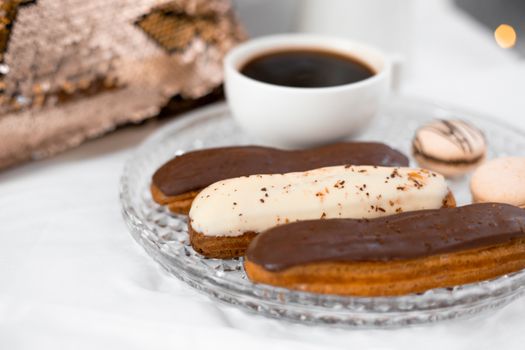 Delicious eclairs with coffee on a glass plate, perfect for gourmet indulgence.