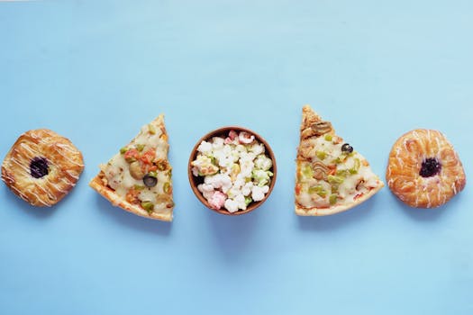 An overhead view of pizza slices, donuts, and popcorn on a vibrant blue background.