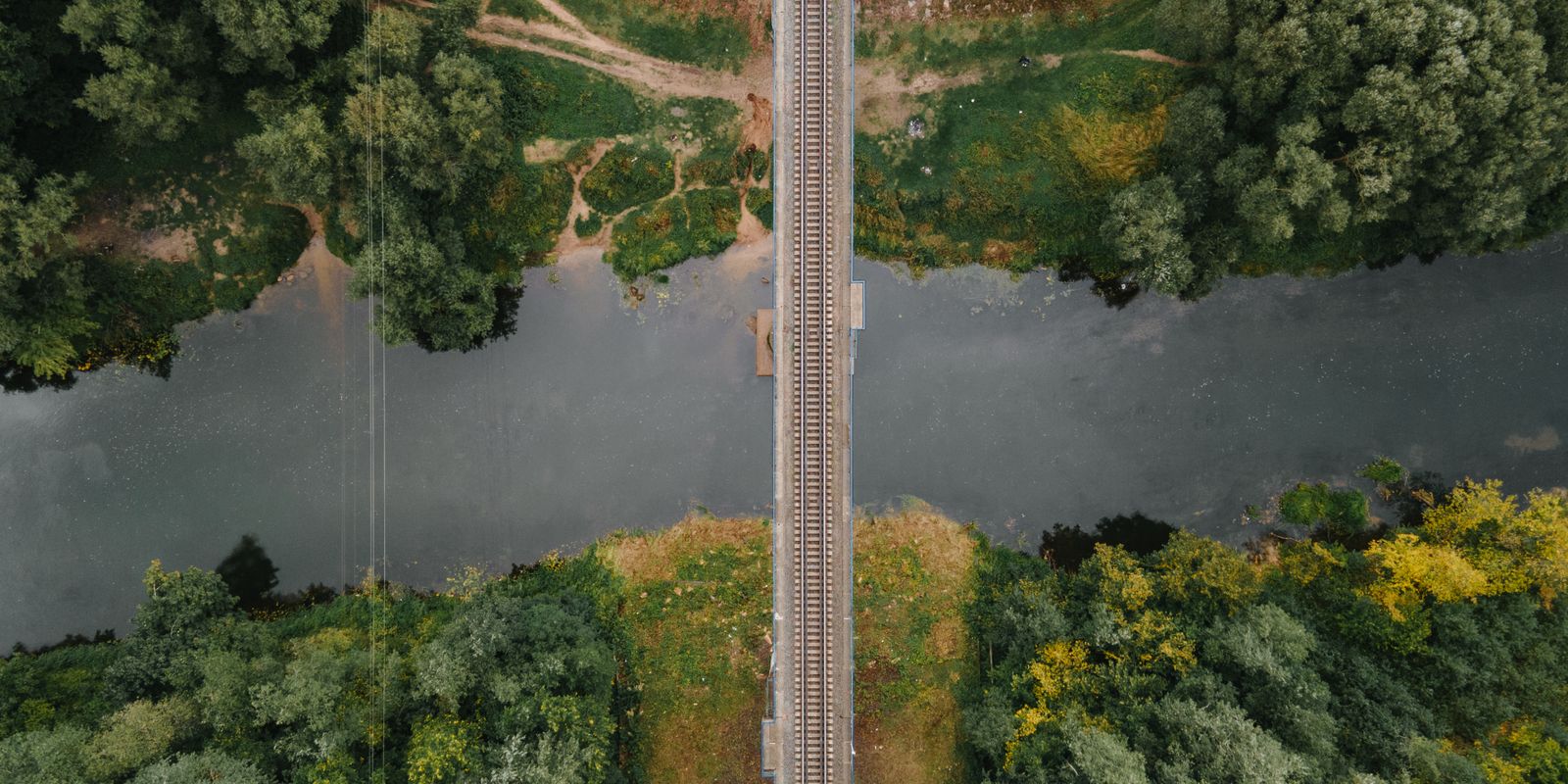 A railway bridge crossing a river through a lush forest