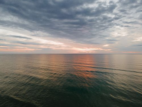 Free A serene ocean view at sunset, with dramatic clouds and a peaceful horizon. Stock Photo