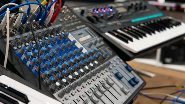 Detailed view of an audio mixer panel and connected synthesizer with colorful cables.