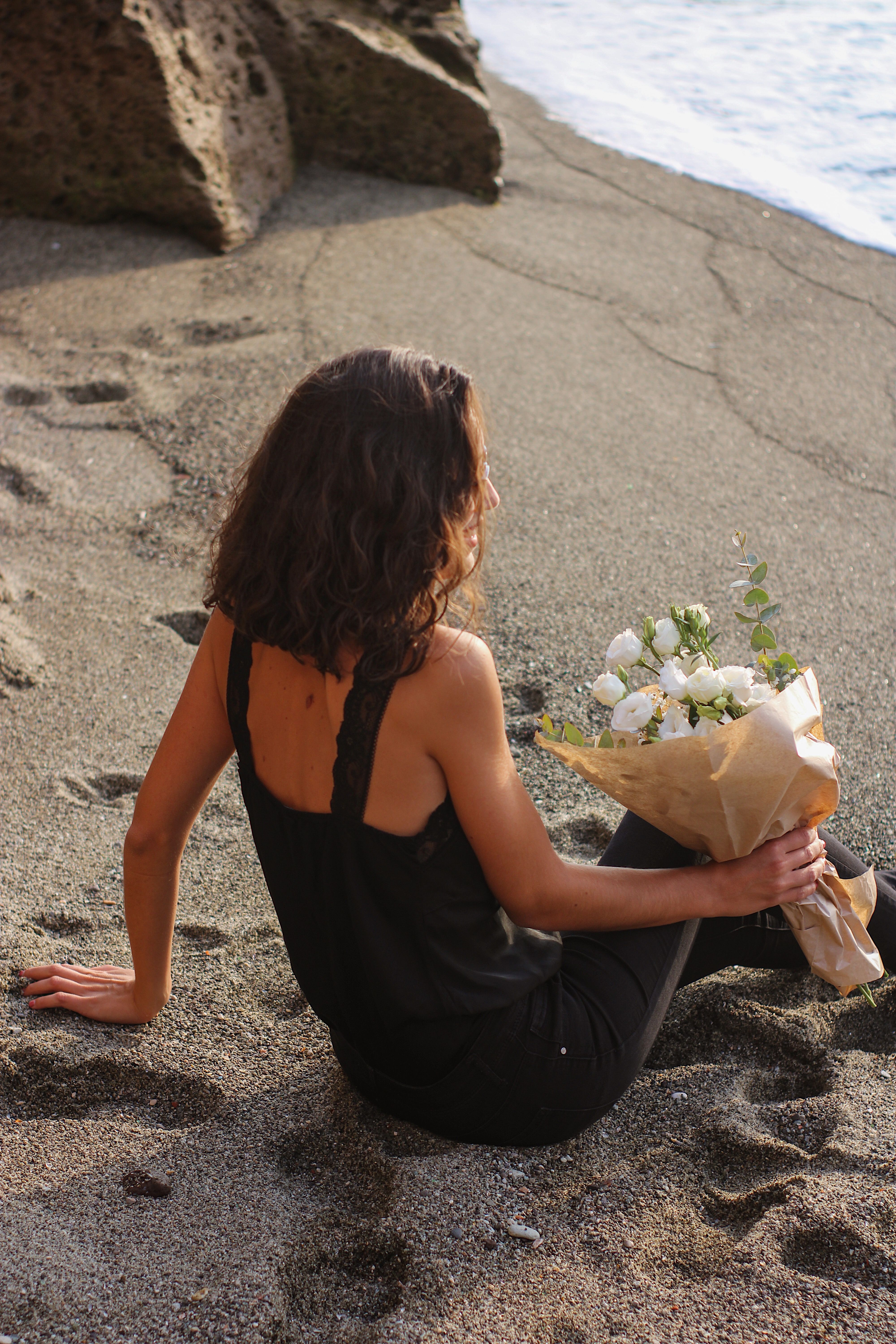 Woman Sitting on the Beach Holding a Bouquet · Free Stock Photo