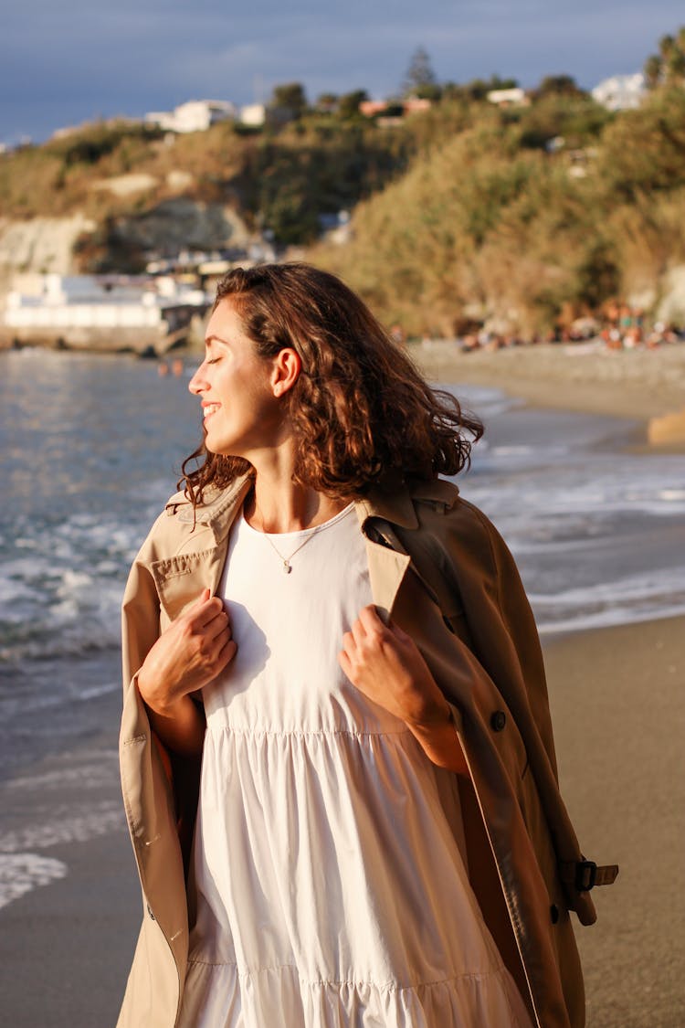 Woman Walking On The Beach In A Coat