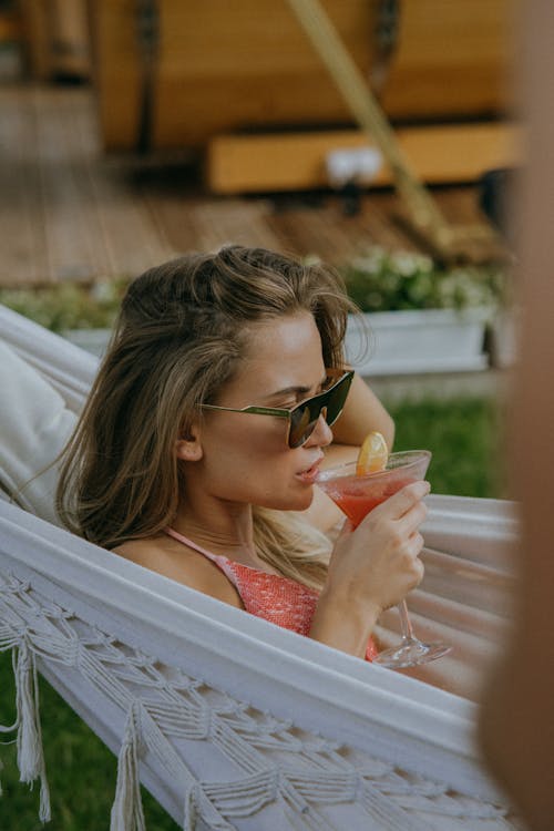 Free Woman Drinking a Cocktail while in a Hammock Stock Photo