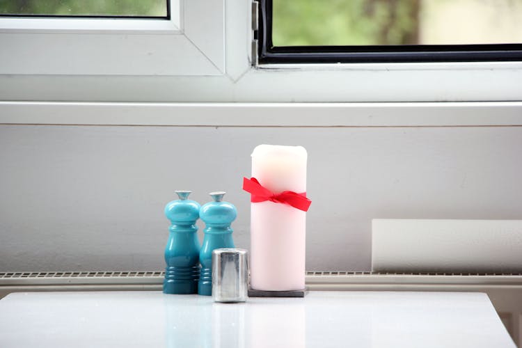 Salt And Pepper Mills Beside A Candle On A Table