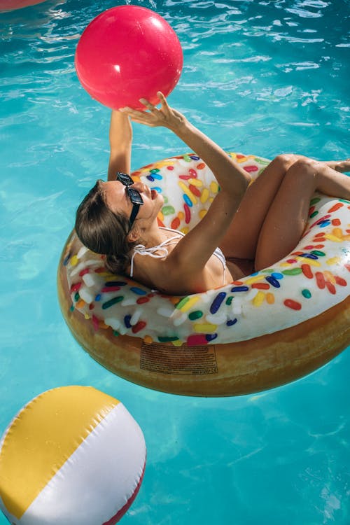 A Woman in a Bikini Lying Down on an Inflatable Floater in a Swimming Pool