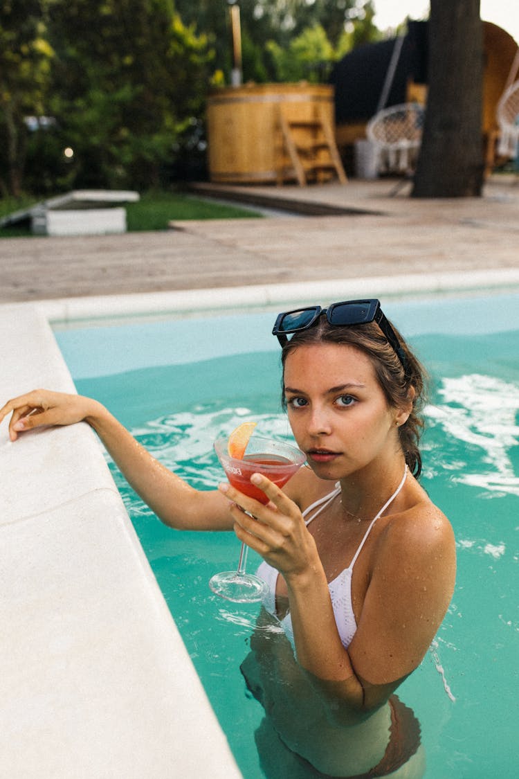 A Woman Drinking A Cocktail In A Swimming Pool