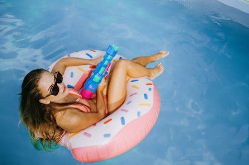免费 一个穿着比基尼的女人在游泳池里的充气漂浮物上 素材图片