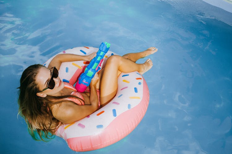 A Woman In A Bikini On An Inflatable Floater In A Swimming Pool