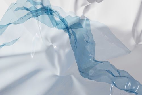 Free A modern abstract art piece with blue translucent fabric creating fluid waves and soft textures. Stock Photo