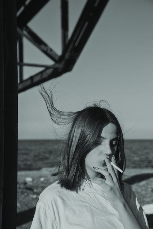 Grayscale Photo of Woman Smoking a Cigarette