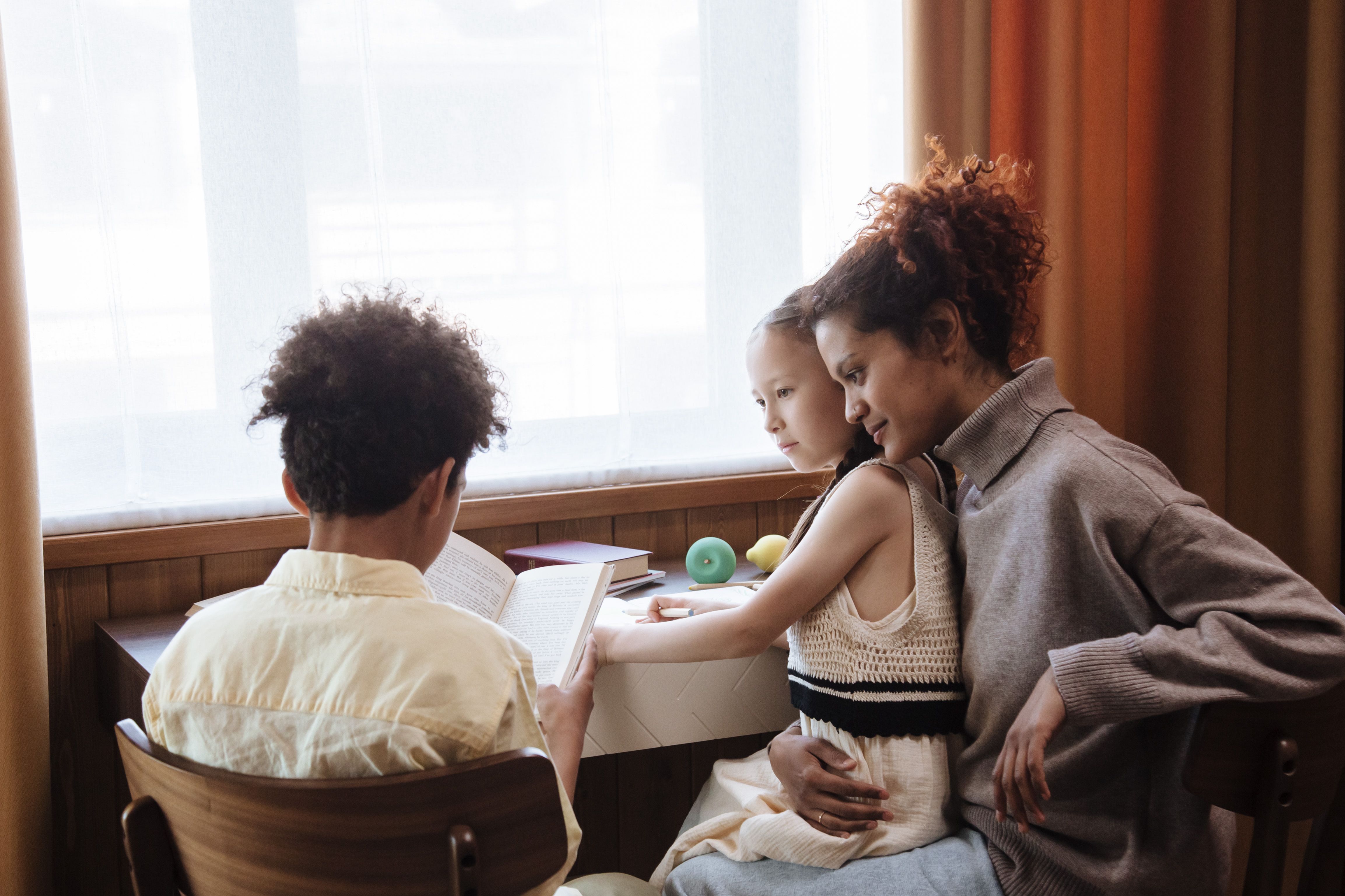 Mother and children enjoying a book together, creating bonding moments in a cozy home environment.