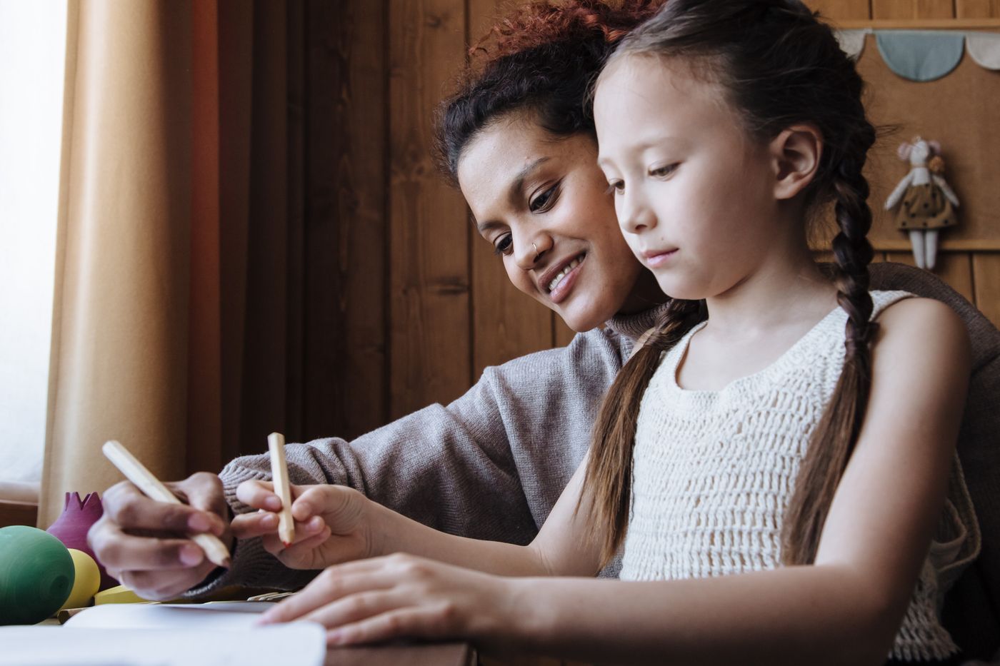 A mother and daughter drawing together at home.