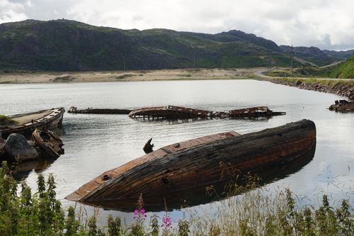 Free Old, decaying boats resting in a tranquil lakeside setting with mountainous scenery. Stock Photo
