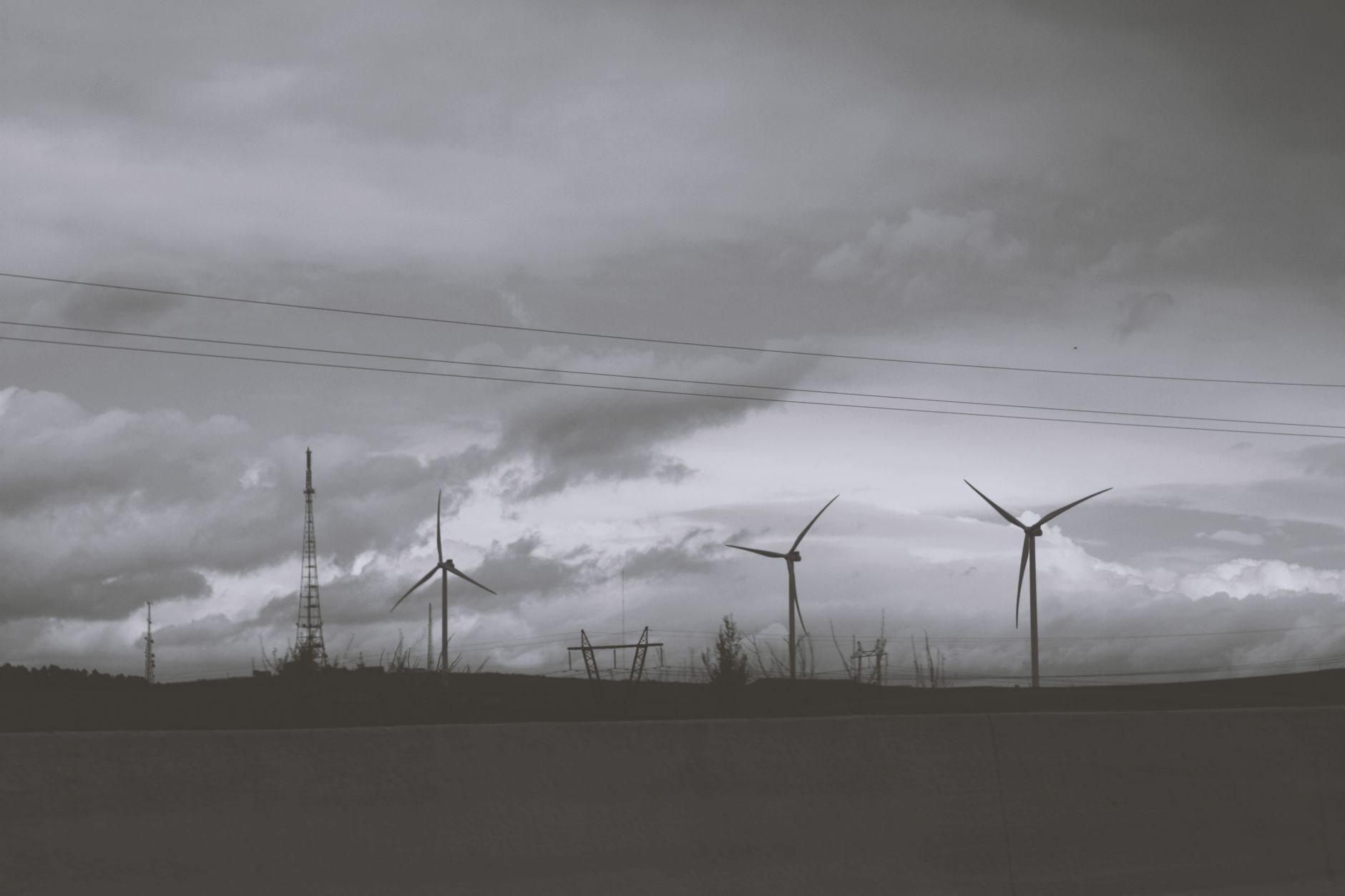 Silhouette of wind turbines against a cloudy sky, symbolizing renewable energy and sustainability.