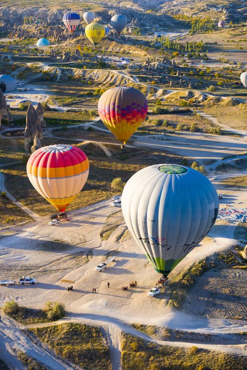 Free Aerial view of vibrant hot air balloons floating over Cappadocia's unique terrain during sunrise. Stock Photo
