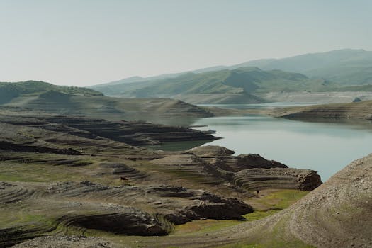 A stunning aerial view of a serene lake surrounded by undulating hills and valleys.