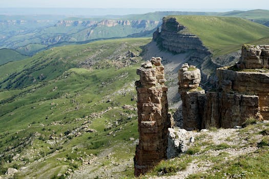 Breathtaking landscape featuring green mountains with unique rocky cliff formations under a clear sky.