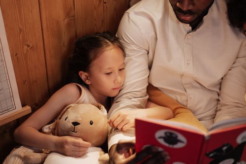 Free A father and daughter share a bedtime story, fostering a warm family bond. Stock Photo