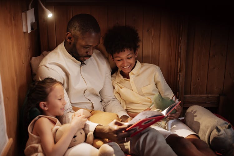 Father With Mother Reading Book To Daughter