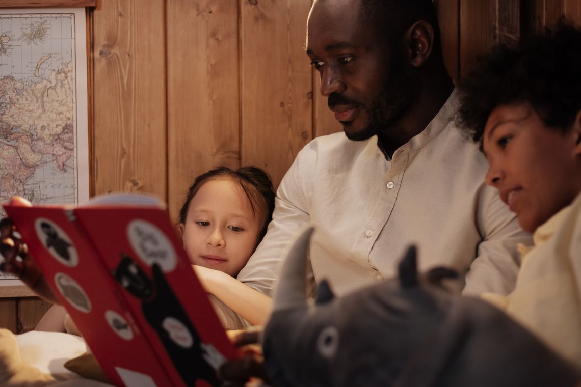 Father reading a storybook with children during family learning time at home