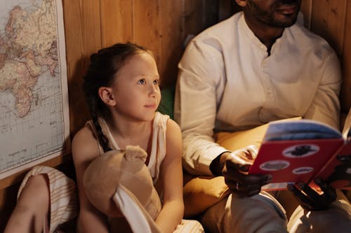 Free Girl Listening as her Father Reads Book Stock Photo