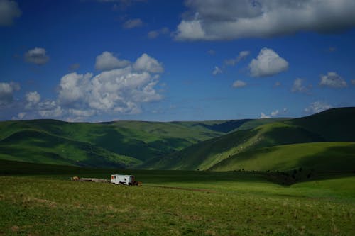 Green Hills and Grasslands under Blue Cloudy Sky 